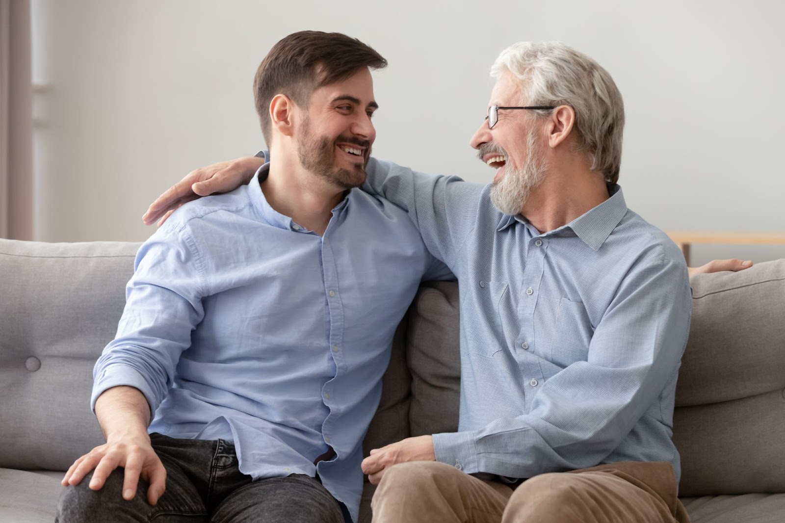 A man and his senior father laughing together as they chat.