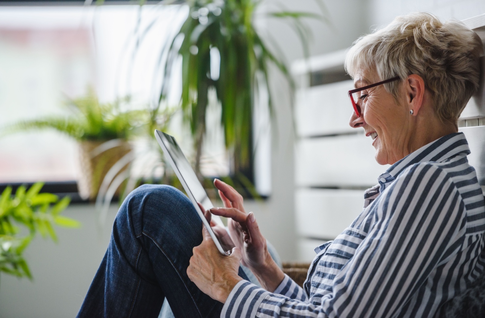 A smiling senior reads an e-book on their tablet.