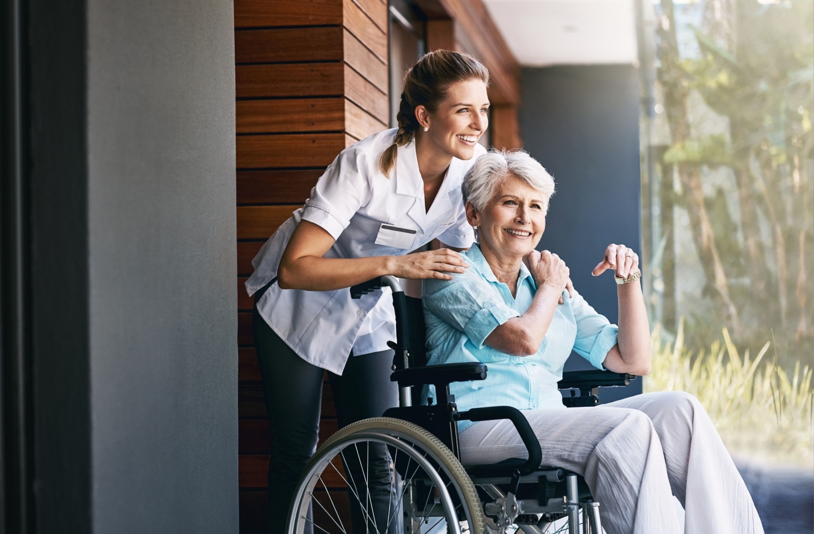 A senior touches their nurse’s hand in thanks after receiving help getting outside to enjoy the warm summer day