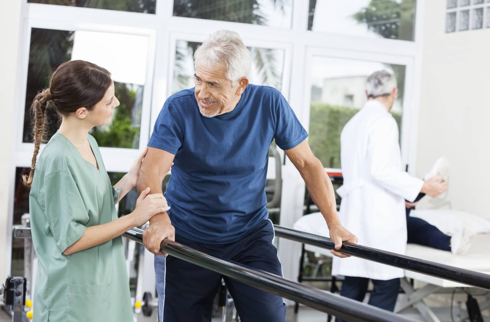 A physiotherapist helps a senior with physical therapy to help restore walking abilities after an accident