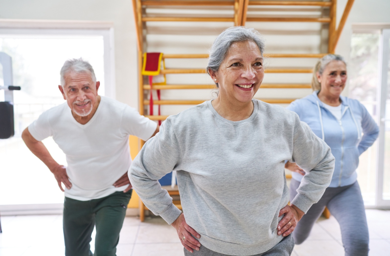 A group of seniors stand with their hands on their hips during an exercise class
