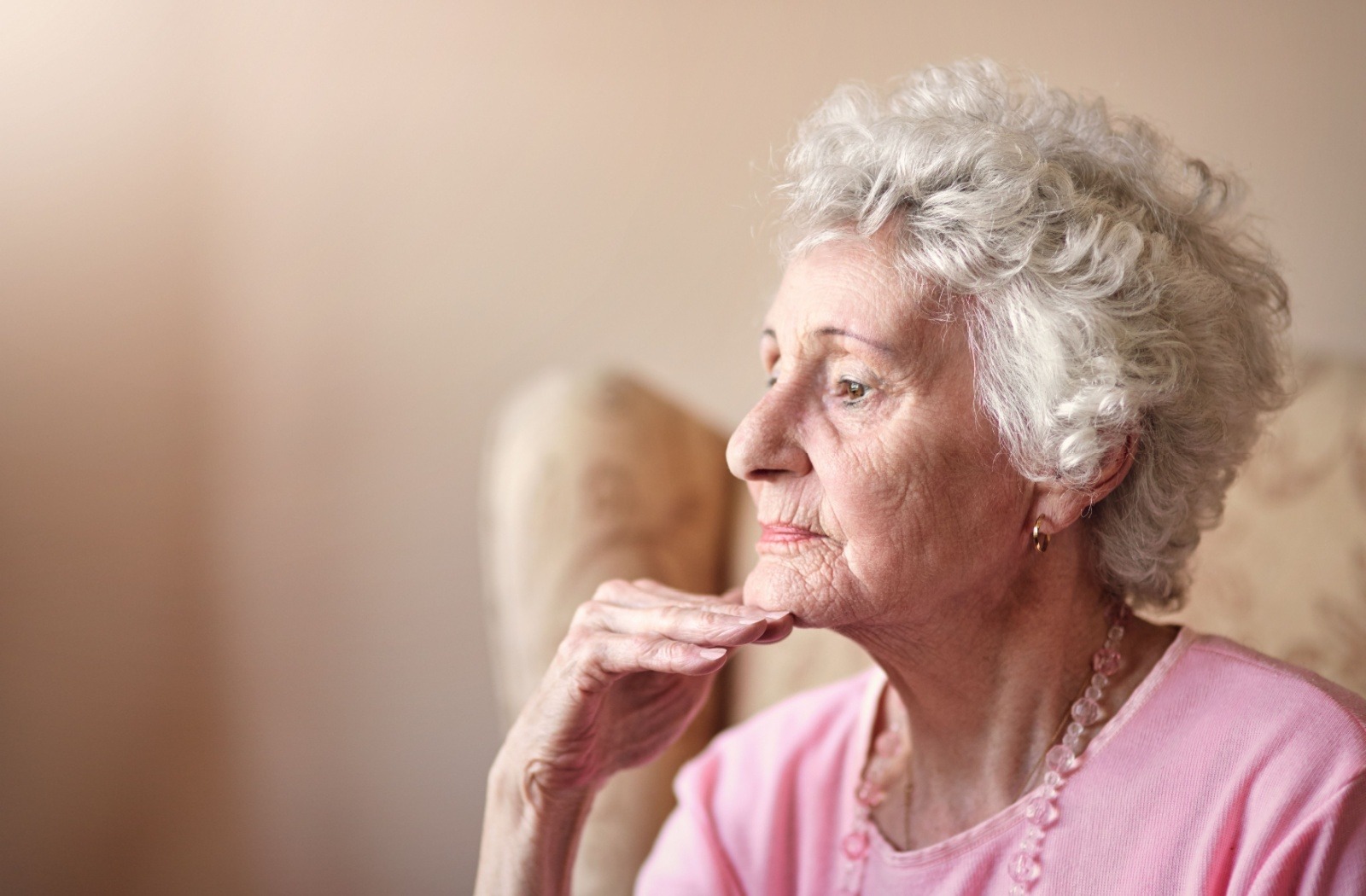 A senior rests their chin on their hand while looking distant and concerned.
