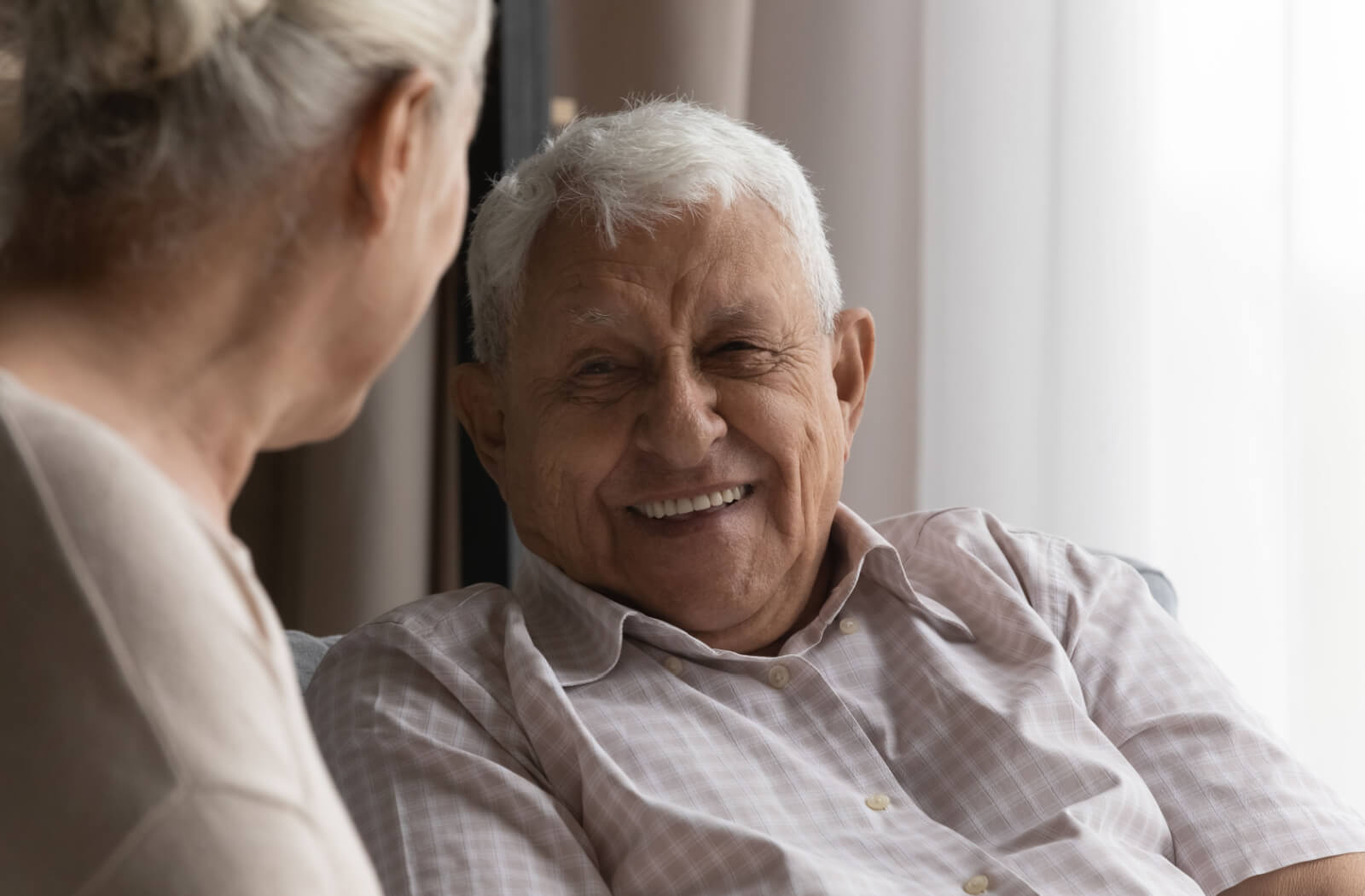 A senior woman, smiling and talking to her senior husband